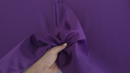 Mână care strânge material violet ferm falduri neregulate volum păstrat la presiune