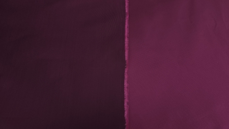 Cele două fețe ale materialului puse una lângă alta stânga bordo prună, dreapta magenta perlat, margine cu franjuri vizibilă