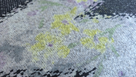 Stofă cu flori mov și galbene, detaliu cu flori galbene și frunze verzi pe fond gri