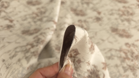Margine tăiată prinsă între degete, cu față crem și revers brun
