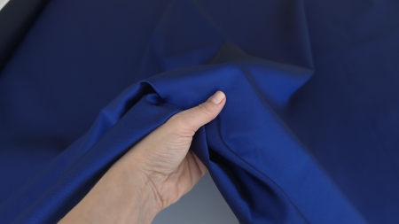 Mână ține colț îndoit în formă de picătură din material indigo, revers mai închis vizibil în interior