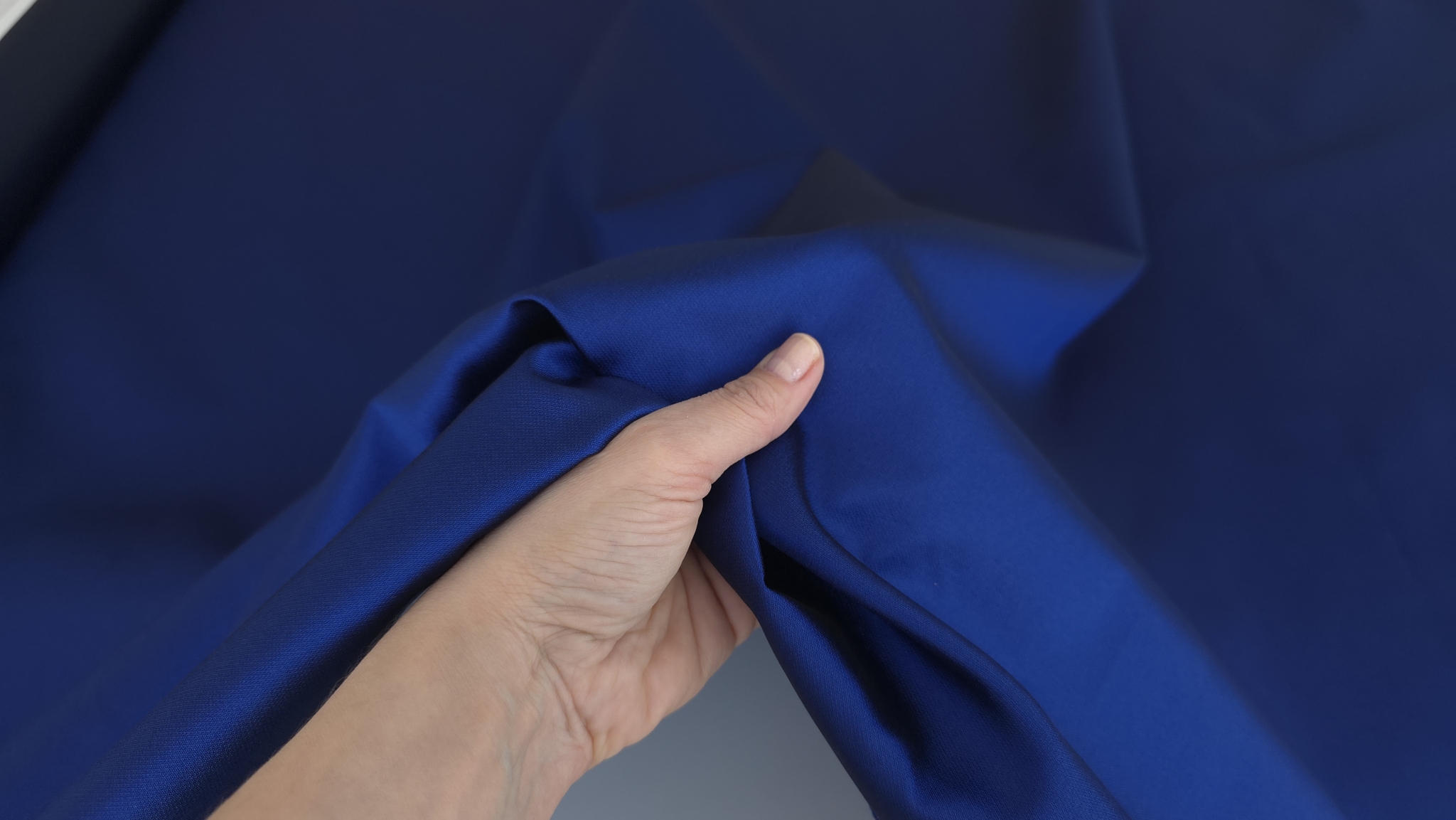 Mână ține colț îndoit în formă de picătură din material indigo, revers mai închis vizibil în interior