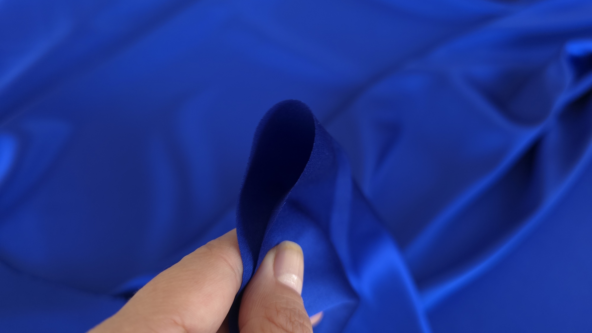 Muchie de material albastru prinsa intre degete cu reversul mai inchis expus