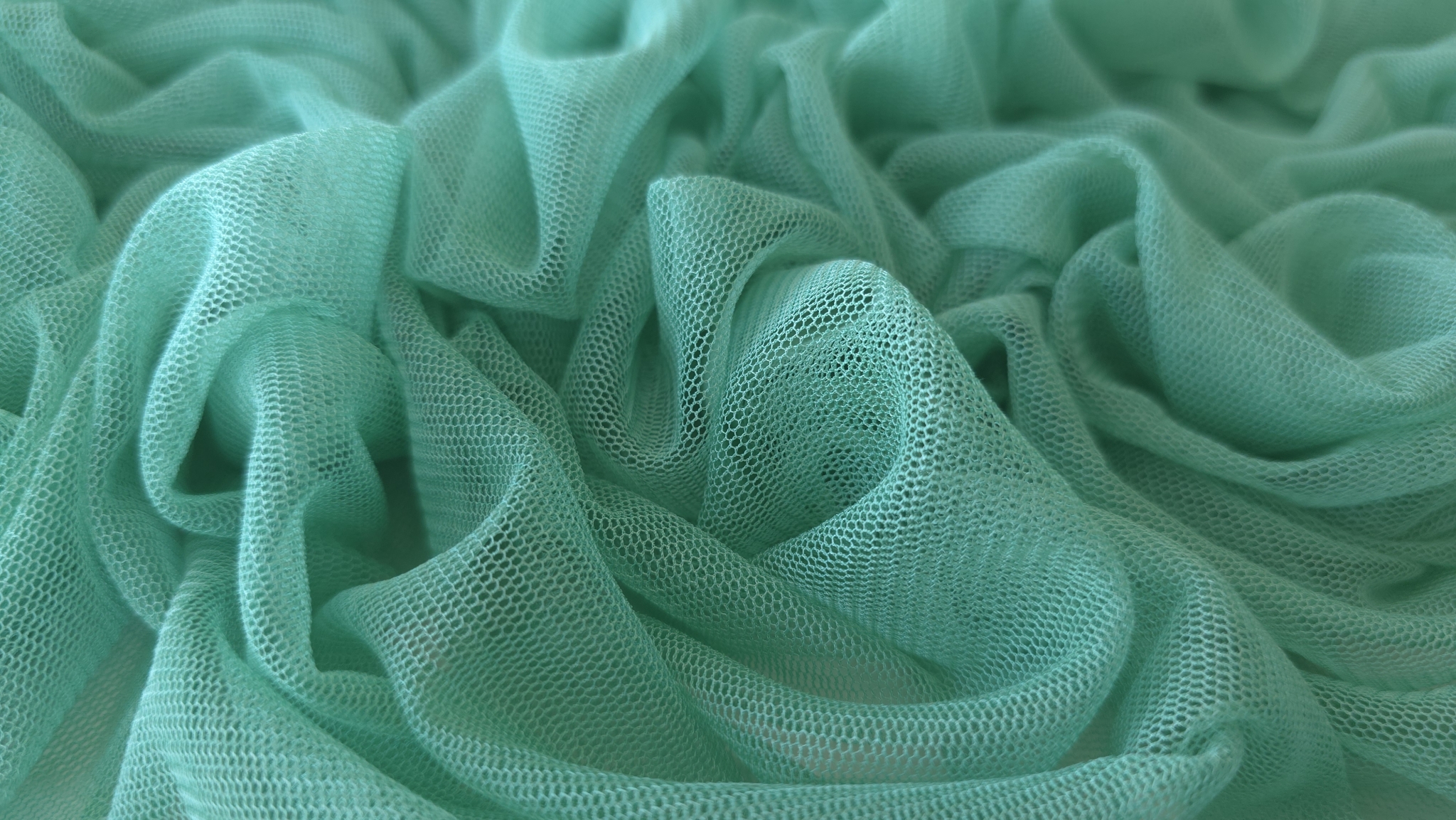 Detaliu apropiat de plasă cu ochiuri hexagonale mici în ton verde aqua