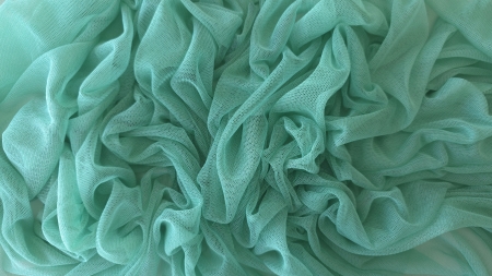 Tul verde aqua adunat în falduri dese pe o suprafață deschisă