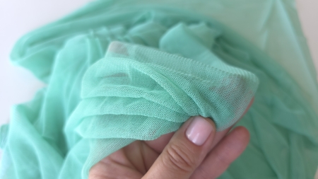 Tul din mătase naturală aqua green metraj ținut în mână între degete