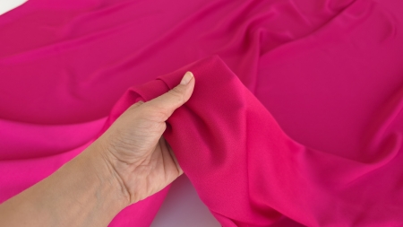 Crep satinat fucsia din fibre naturale MRN1168 ținut în palmă, cu suprafață lucioasă