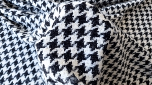 Stofa tip chanel cu lana bicolor ținută în mână, cu model pied de coq negru și ivoire