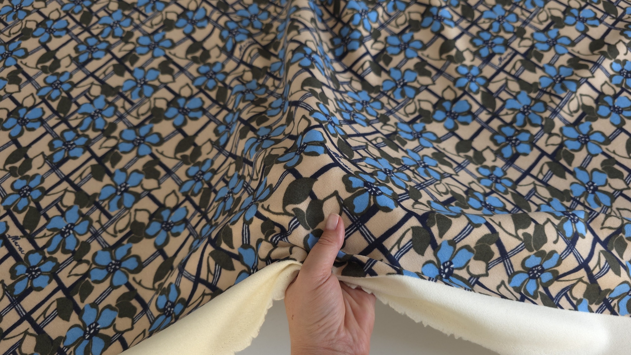 Material cu model de petale ținut în mână, cu dosul crem la vedere