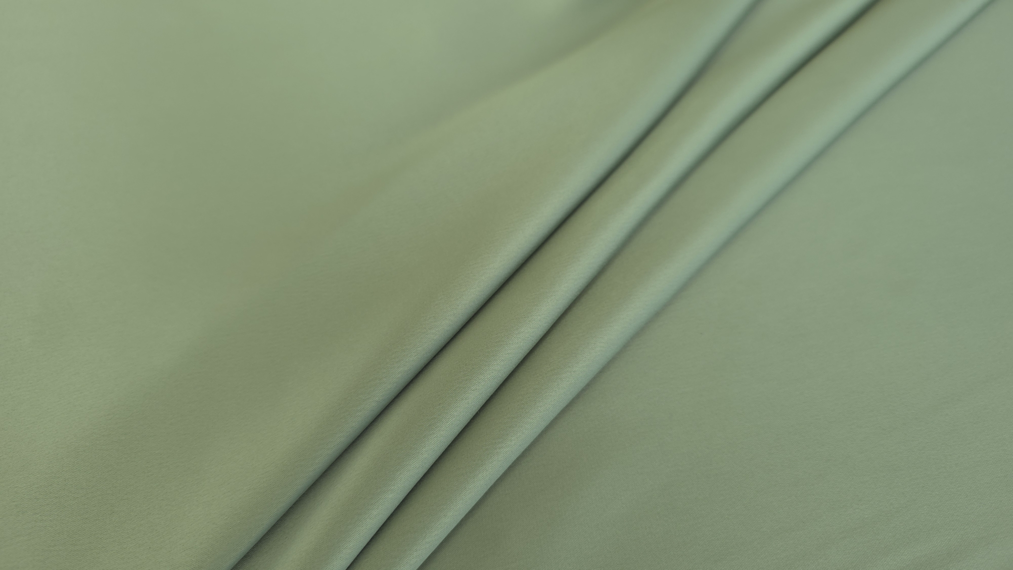 Două pliuri diagonale pe suprafață netedă verde olive cu reflexie liniară a luminii