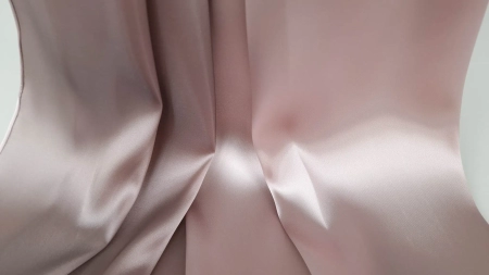 Căderea naturală a unui material satinat roz pal cu verso negru vizibil