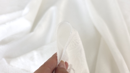 Marginea țesăturii off white ținută între degete