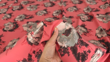 Material pink cu flori negre și gri ținut în mână, cu zone metalizate