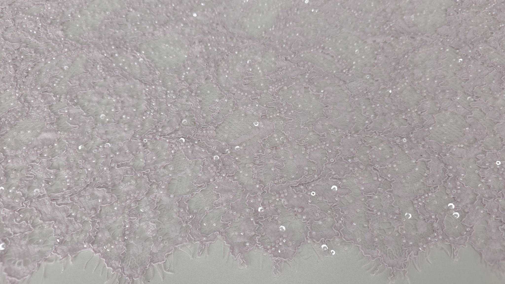 Bordură scalopată cu gene fine pe marginea materialului roz pastel