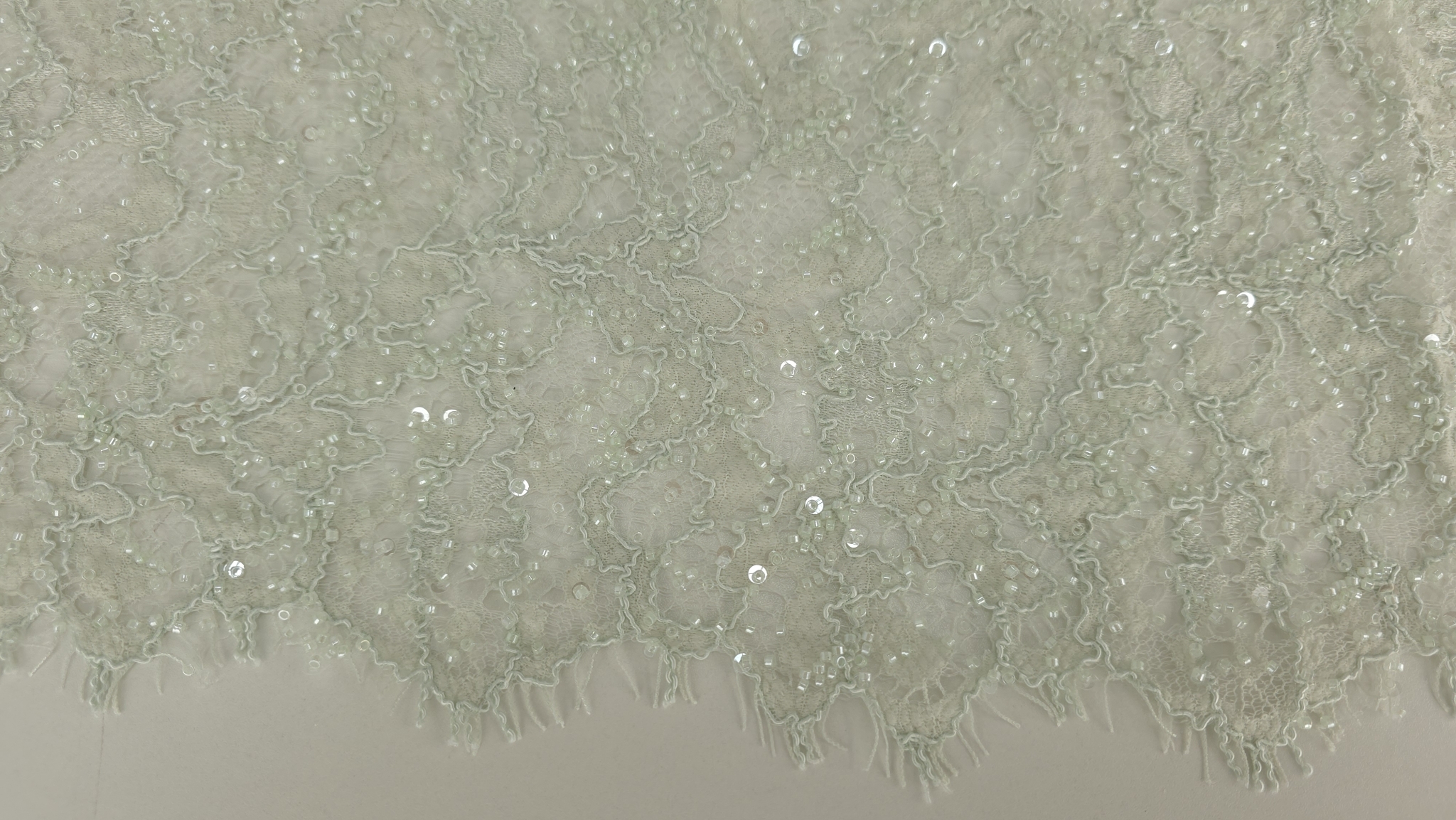 Bordură scalopată cu gene fine pe marginea materialului verde pastel