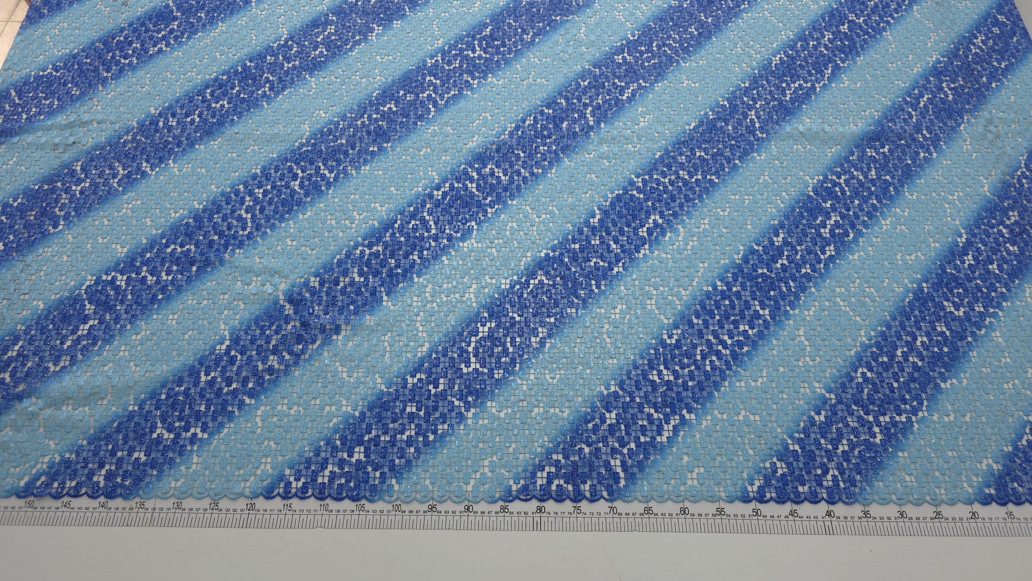 Broderie albastră în degrade cu paiete și fir metalizat, vedere de ansamblu pe masă cu riglă