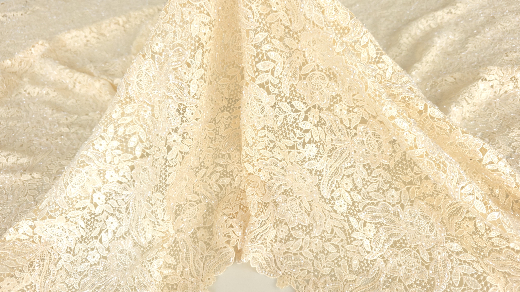 Broderie champagne cu margele la metru fotografiată de aproape cu motive florale vizibile