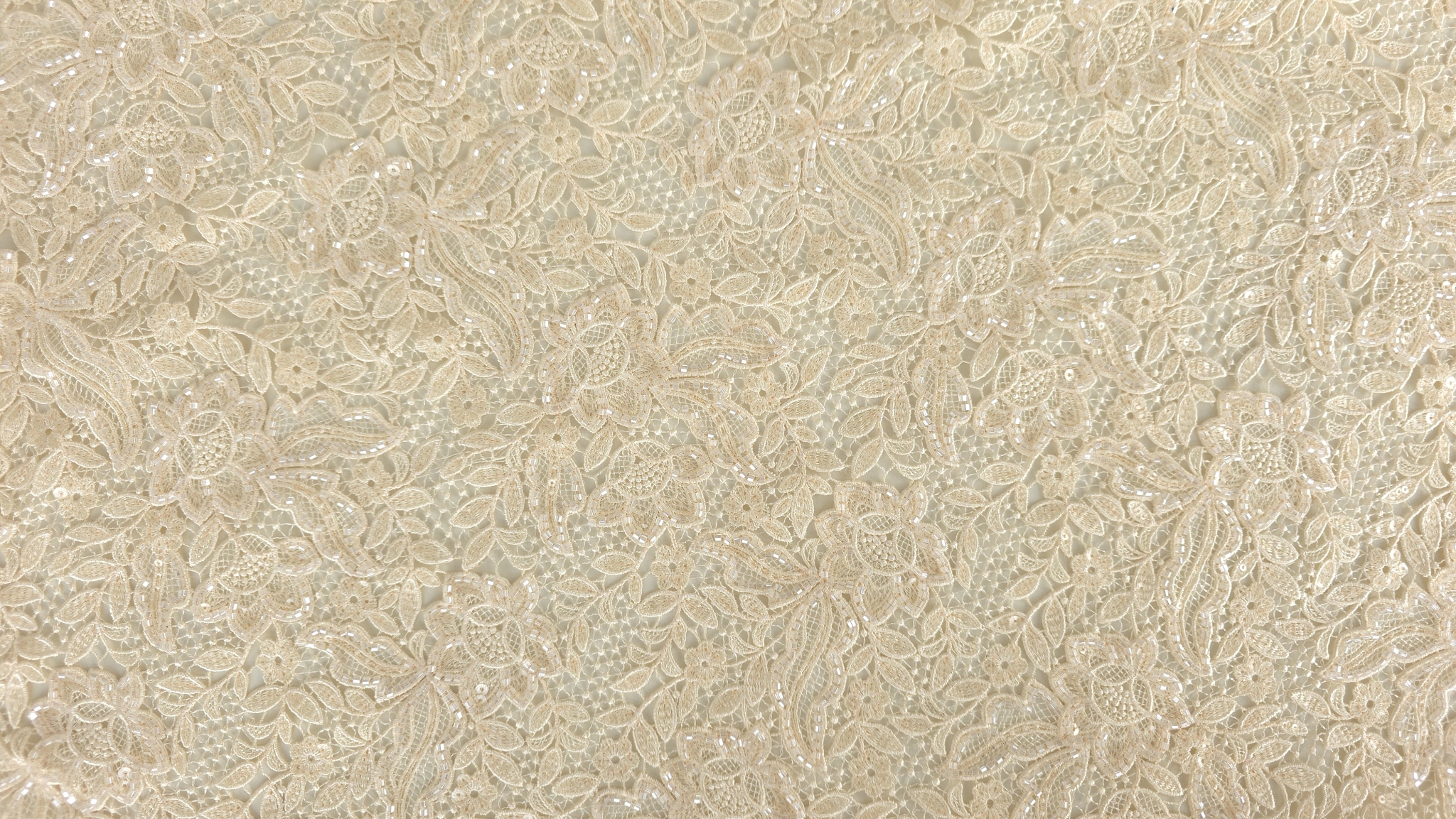 Broderie champagne cu margele prezentată în plan general pe suprafață albă