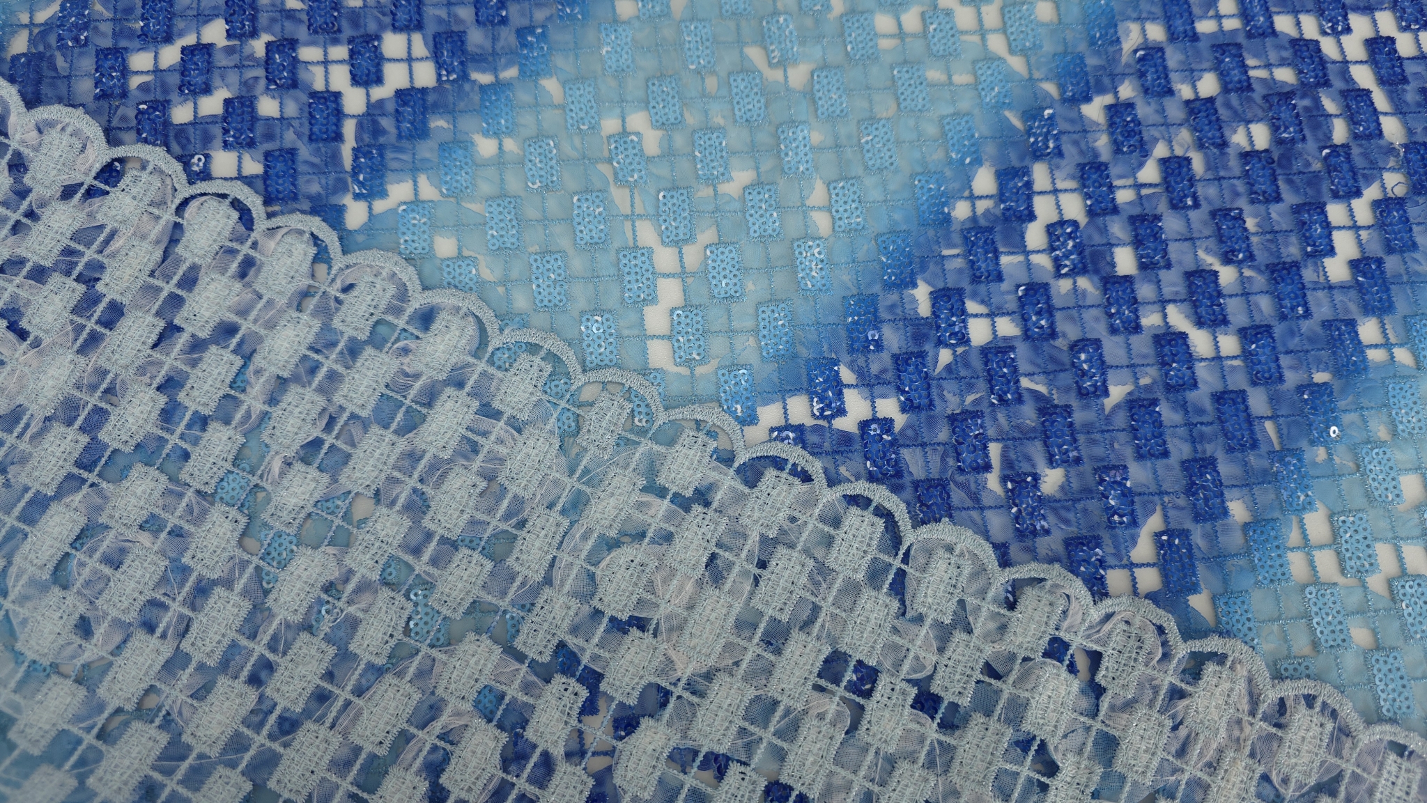 Broderie degrade albastră pe fond transparent cu benzi diagonale și bordură scalop vizibilă