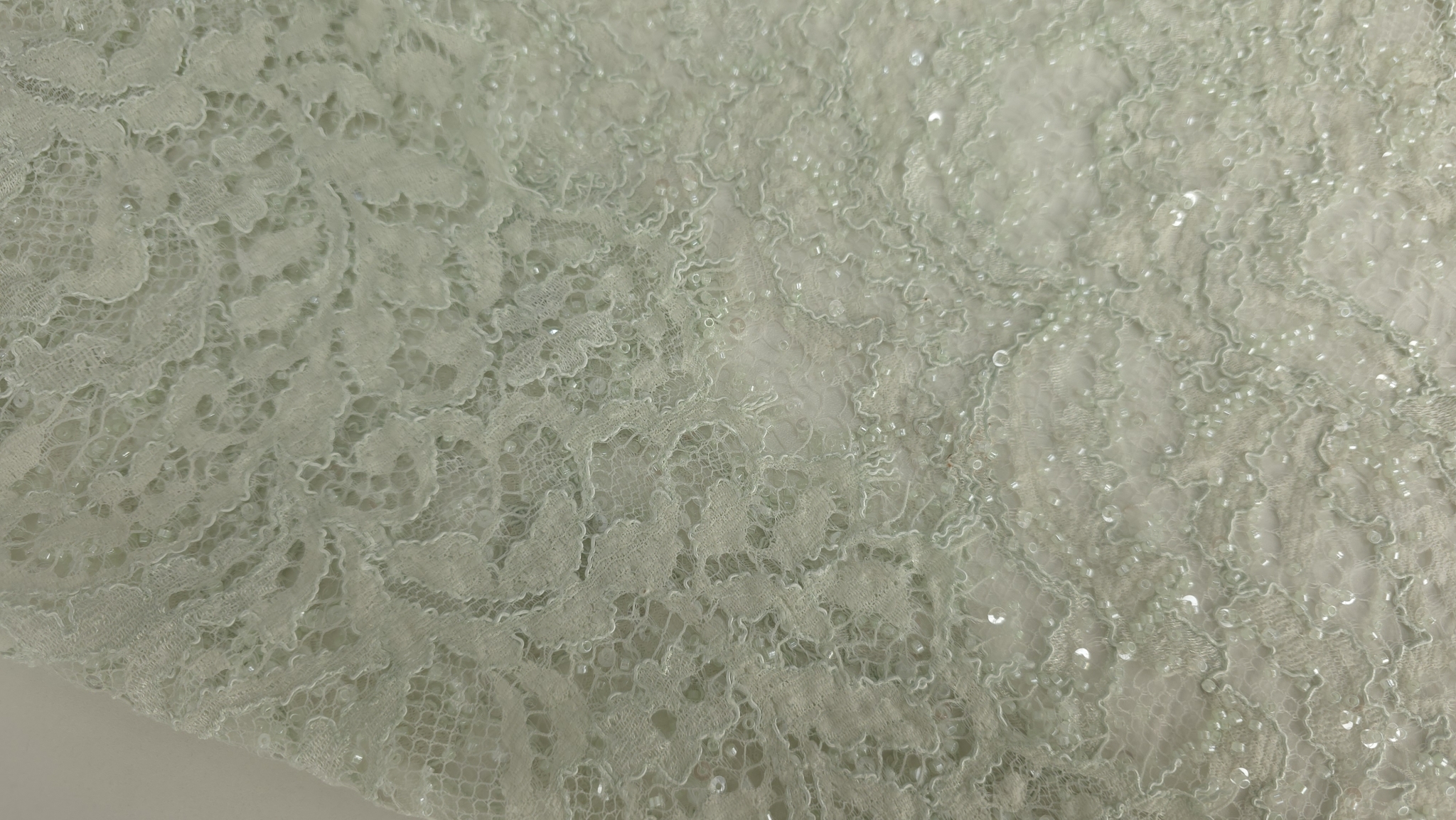 Broderie florală pe tul verde deschis cu aplicații transparente, plan apropiat