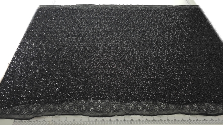 Material negru accesorizat întins pe masă de croit cu centimetru vizibil