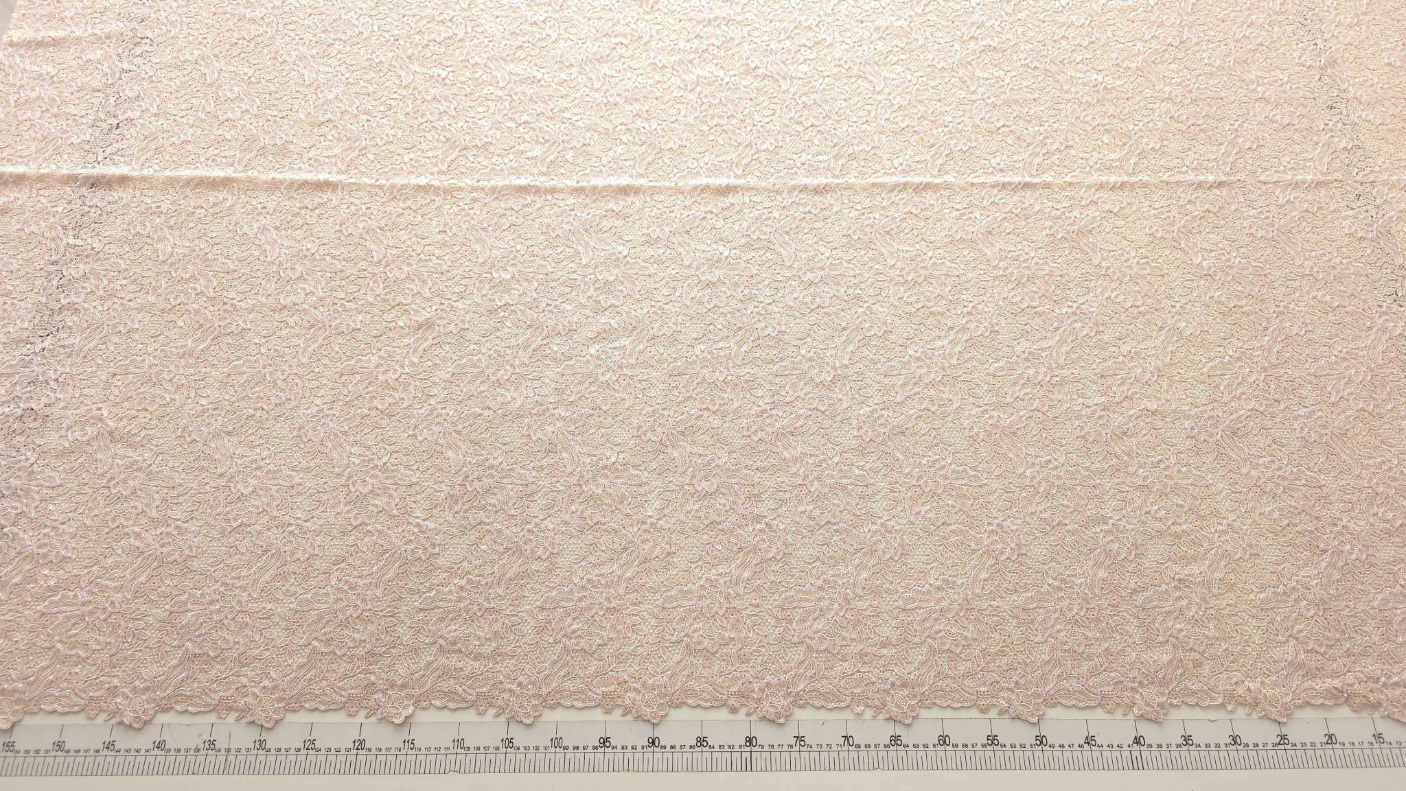 Metraj brodat roz cu aplicații decorative desfăcut pe masă de tăiere