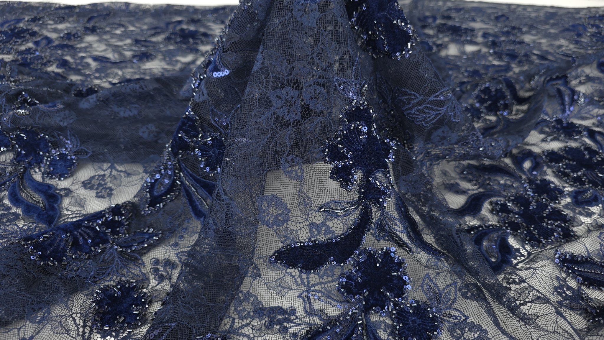 Caderea materialului bleumarin cu flori din catifea și margele pe tulle