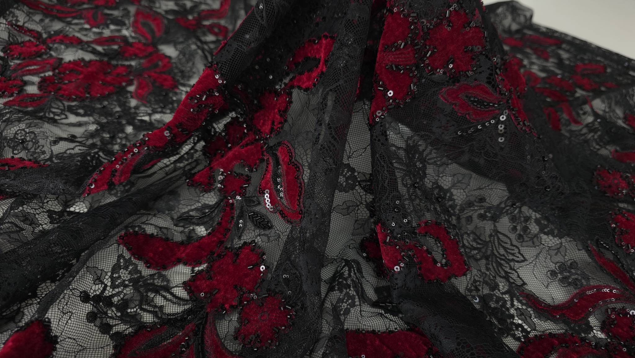 Caderea materialului cu flori roșu sânge și margele pe tulle negru transparent