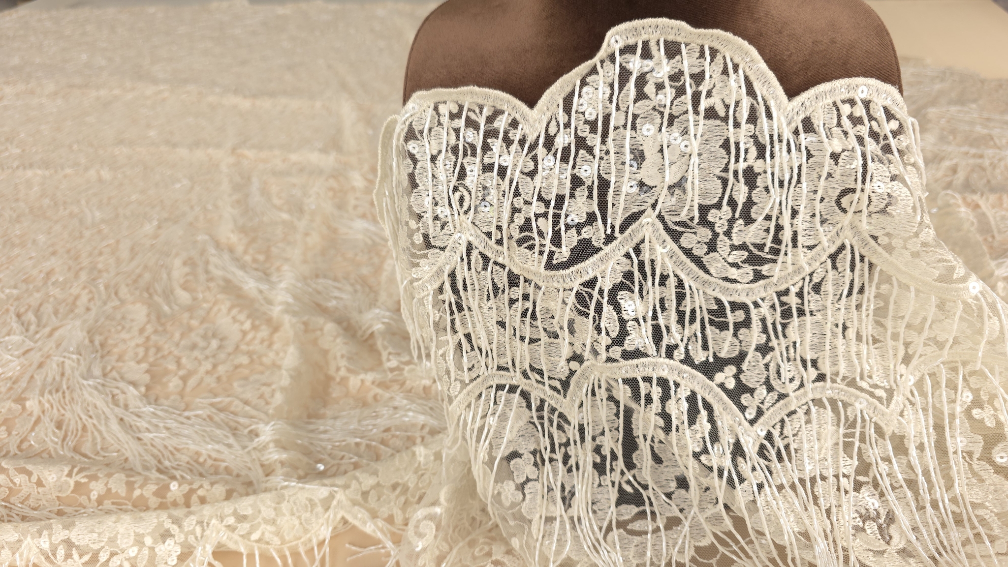 Dantelă accesorizată cu paiete și șiraguri de mărgele prezentată pe manechin maro