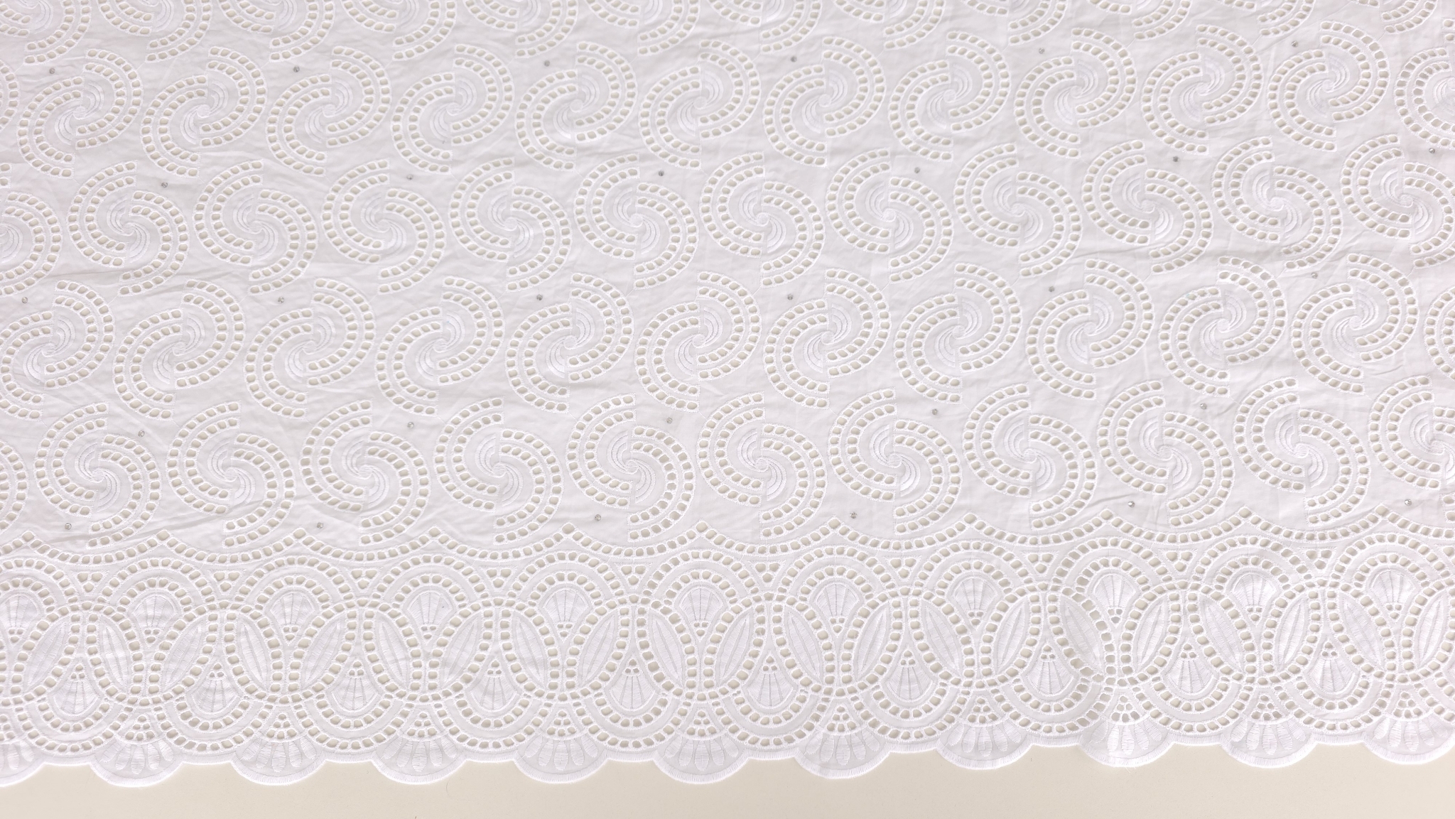 Dantelă albă brodată spartă cu cristale Ariana, vedere de ansamblu pe masa de croit cu riglă de măsurat