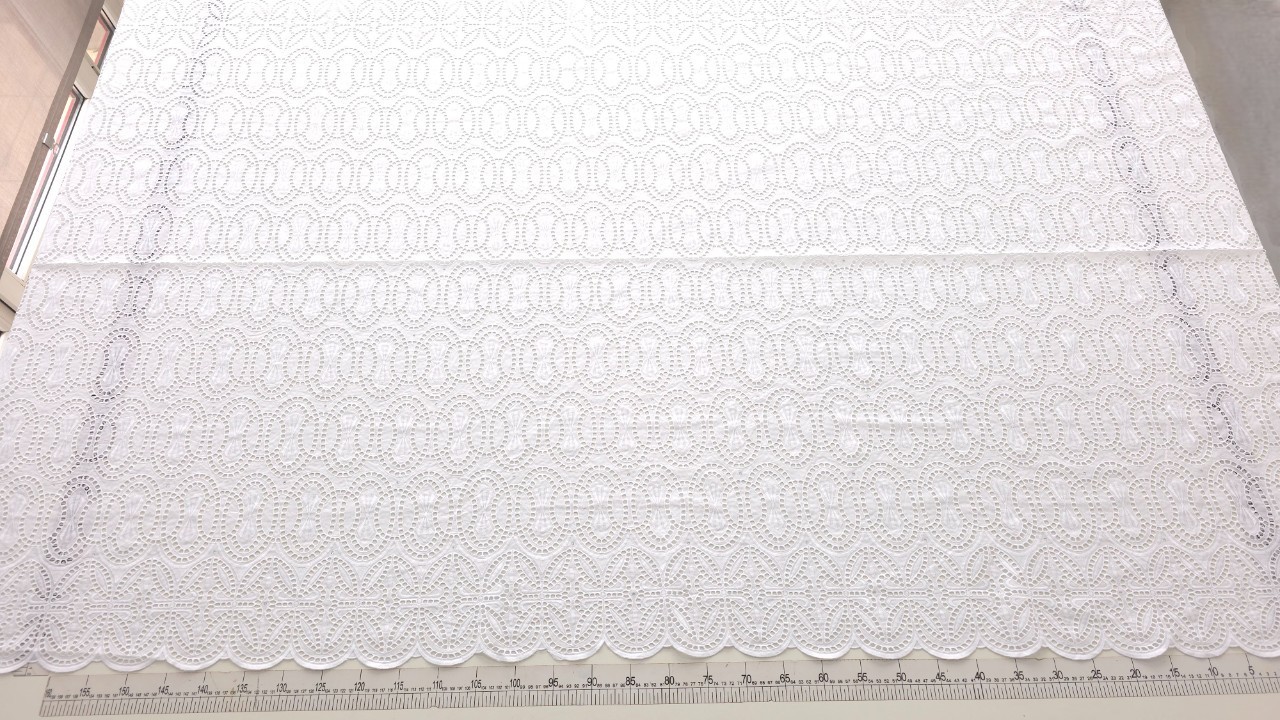 Dantelă albă brodată spartă cu cristale Seraphina, vedere de ansamblu pe masa de croitorie cu riglă