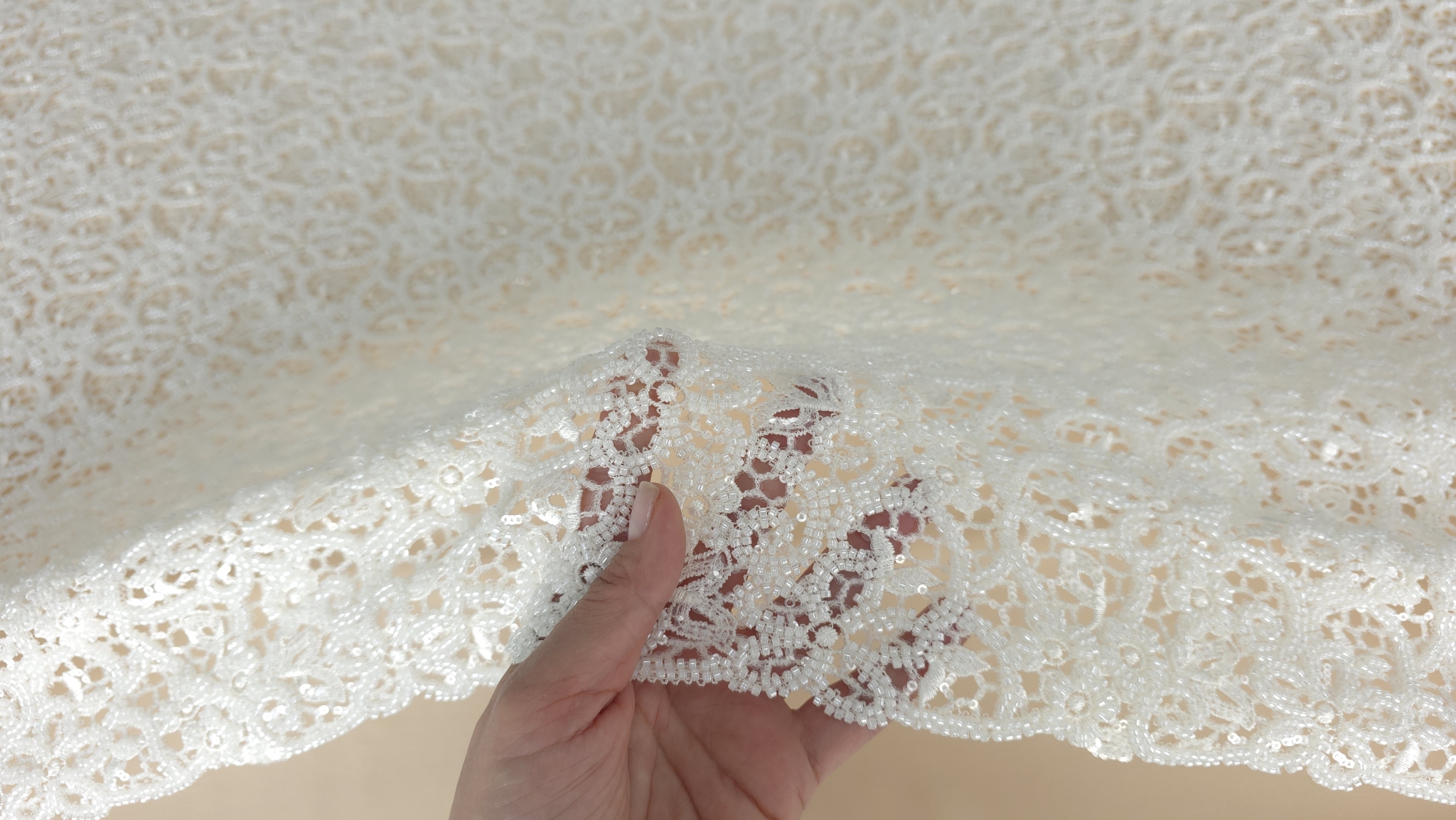 Dantelă brodată ivory cu aplicații strălucitoare formând falduri pe masă