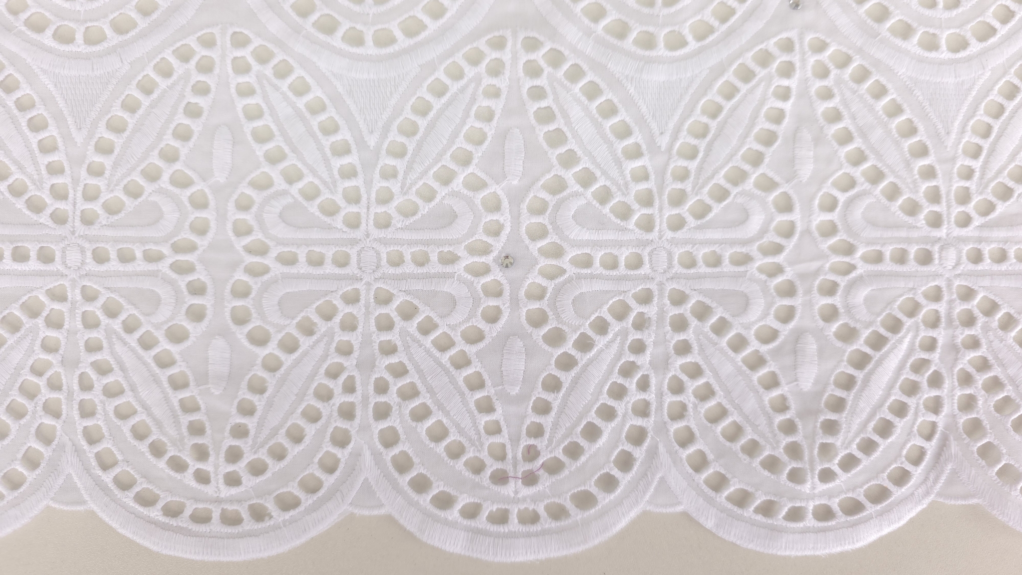 Dantelă brodată spartă cu cristale Seraphina ținută în mână, transparență vizibilă prin perforații