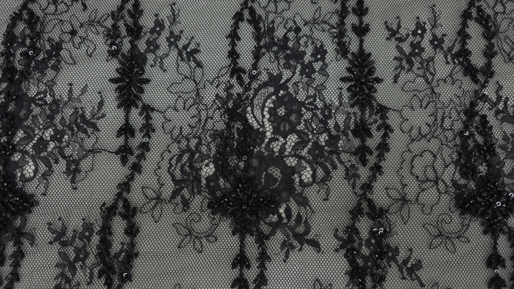 Dantelă chantilly neagră cu mărgele și paiete desfășurată pe toată lățimea materialului