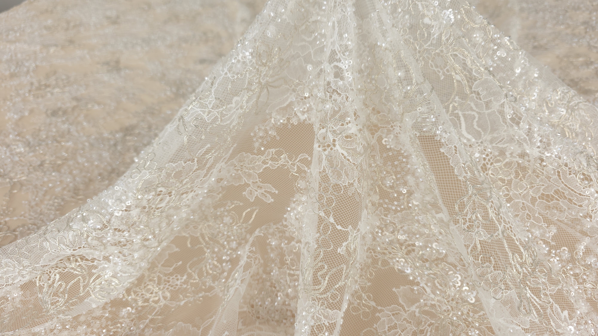 Dantelă fină Chantilly ivory la metru formând falduri ample pe masă