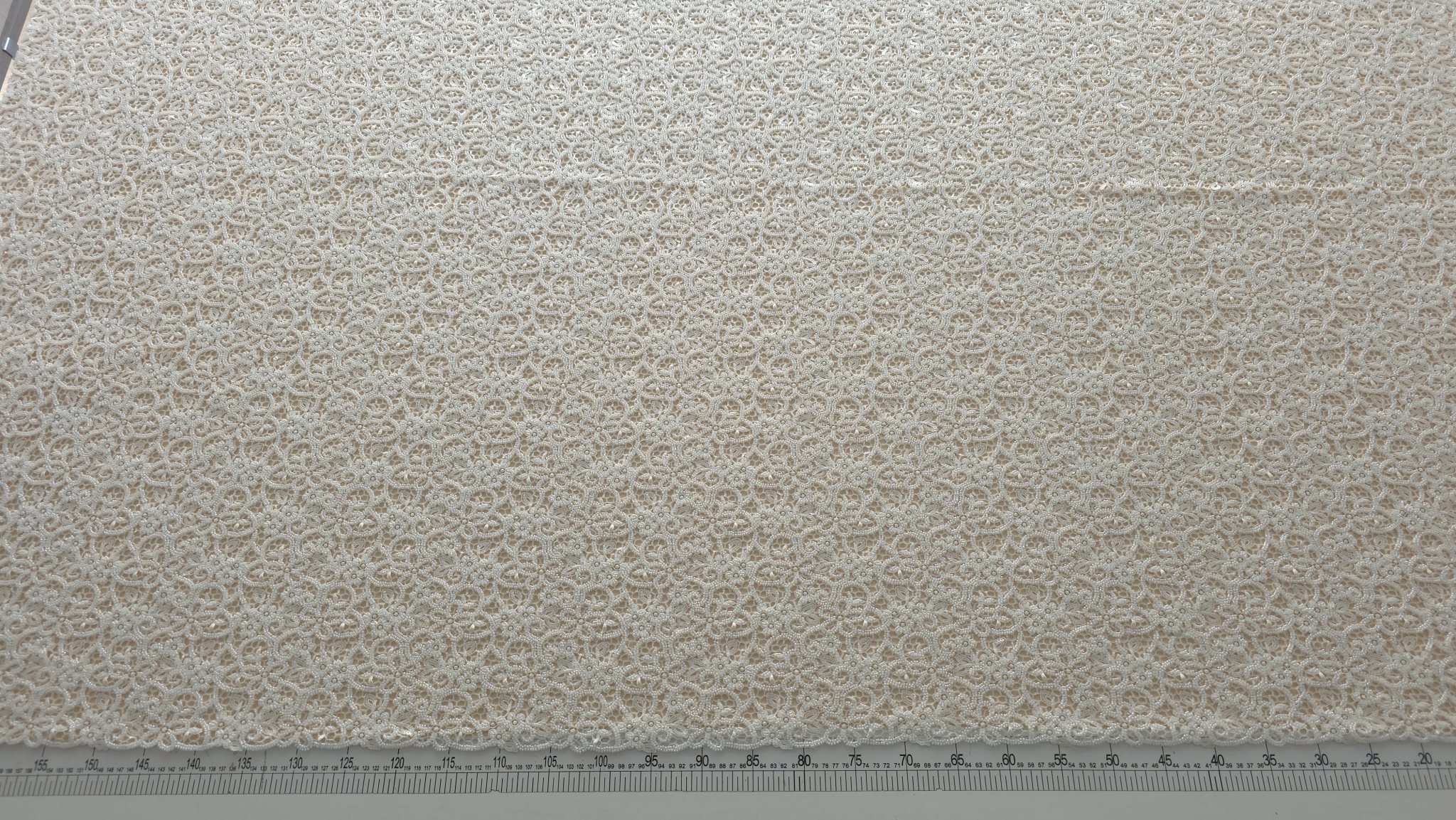 Dantela ivory cu margele si micropaiete prezentată pe fond deschis