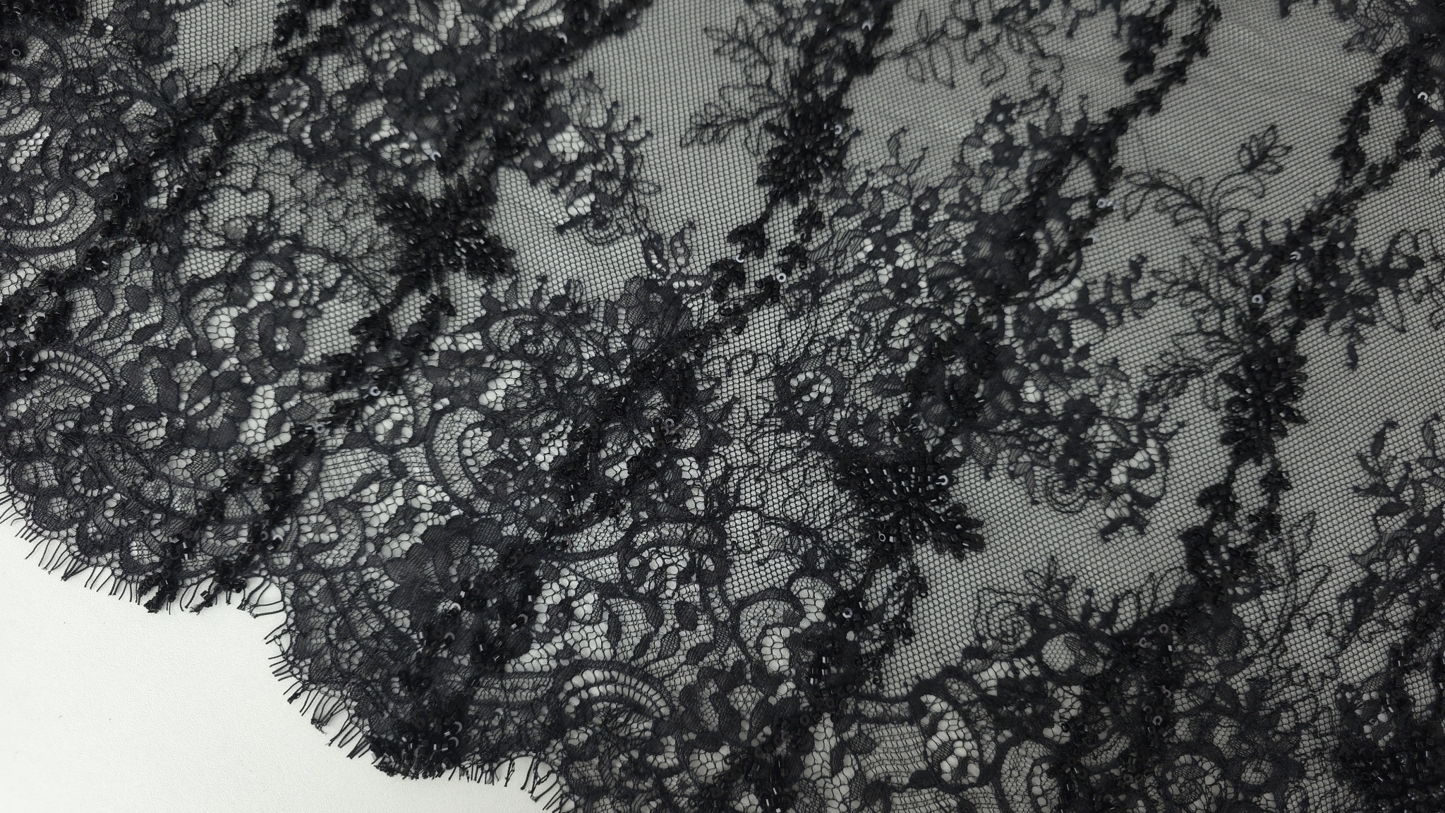 Dantelă neagră accesorizată cu mărgele fine, plan apropiat pe conturul broderiei