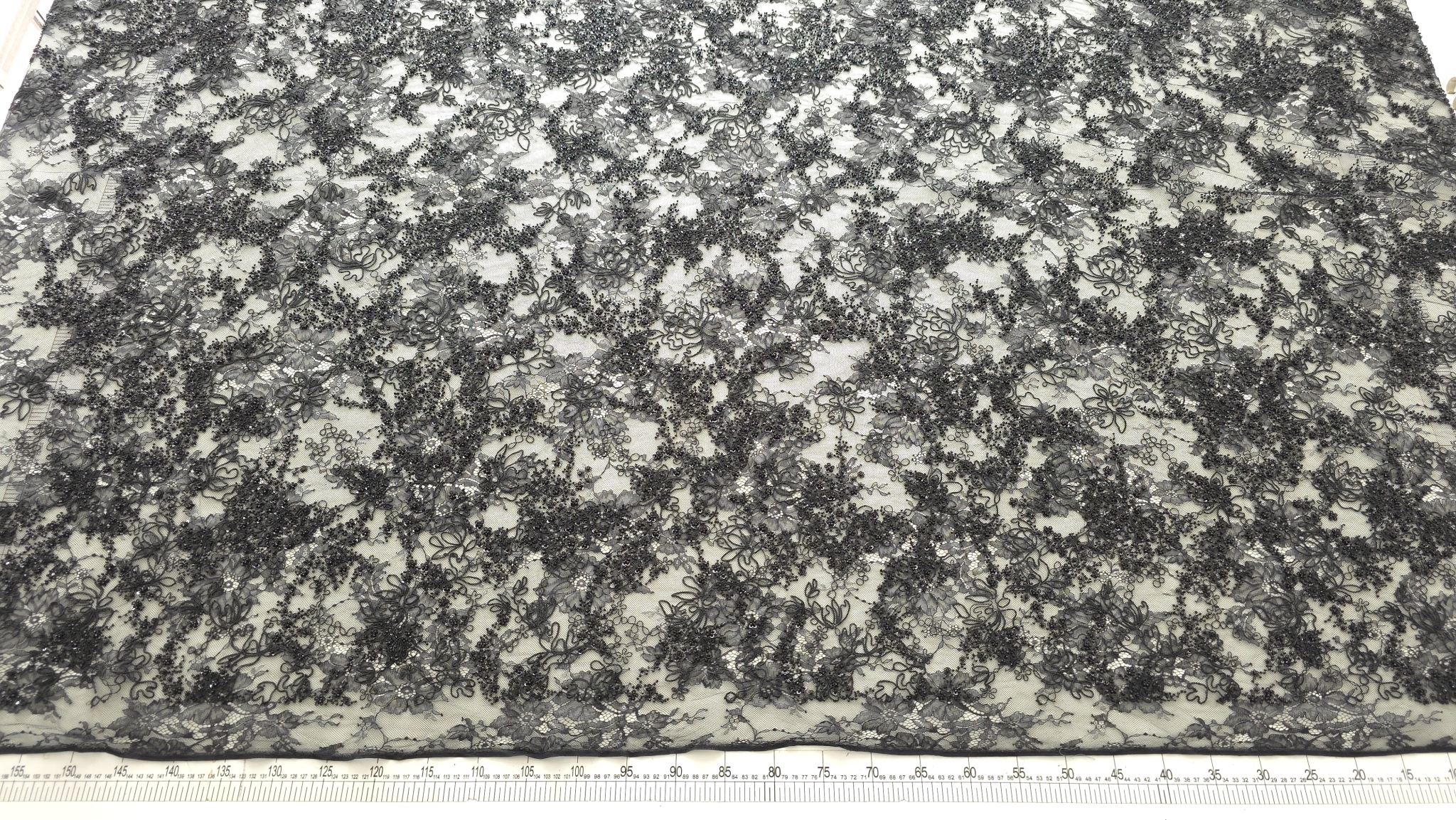 Dantelă neagră tip chantilly rebrode cu margele și paiete prezentată în plan general