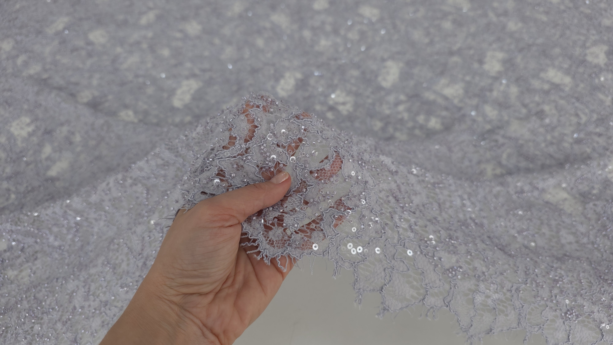 Dantelă gri lila cu bordură dublă și aplicații, degete vizibile prin tul transparent