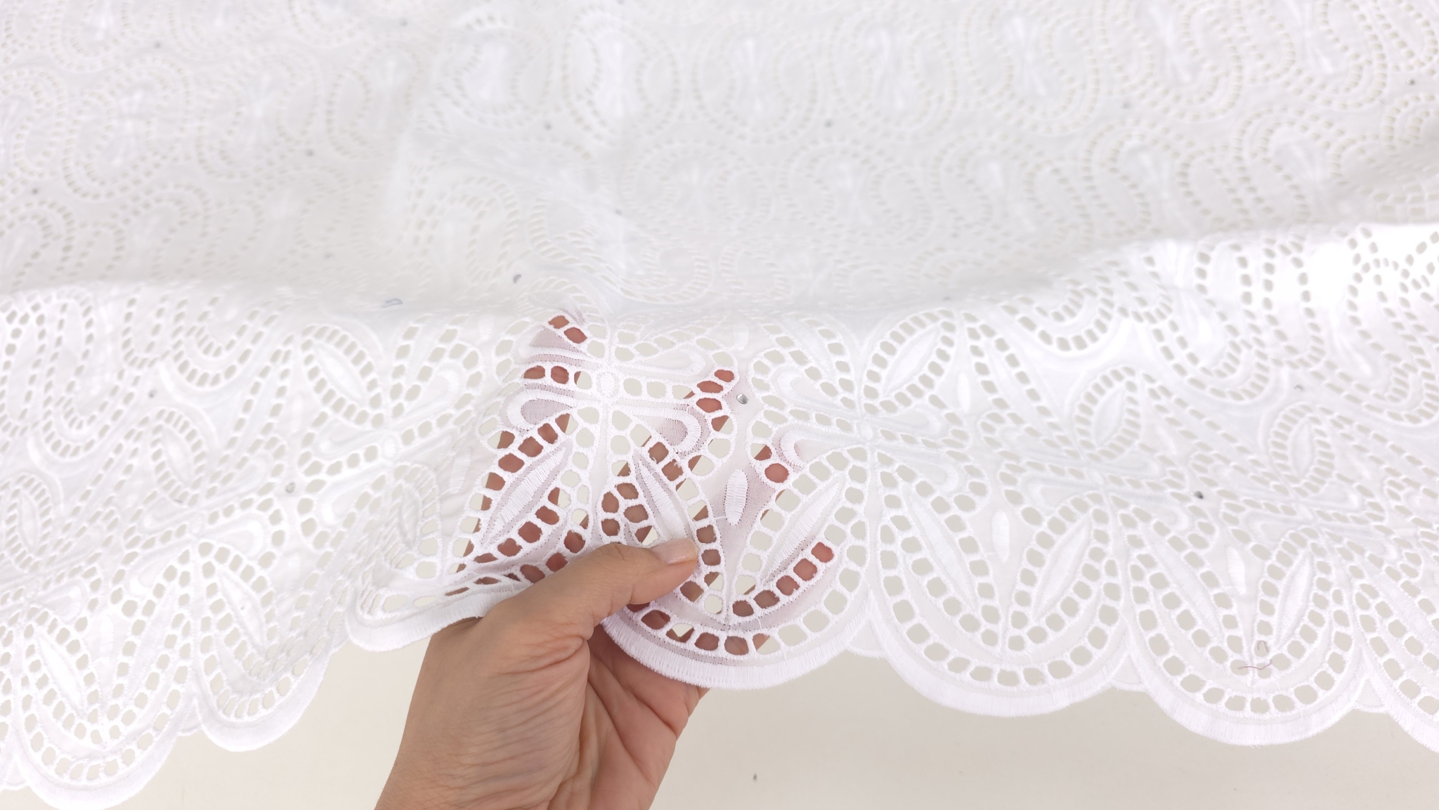 Detaliu arcade ovale brodate cu șiruri de perforații pătrate pe dantelă albă