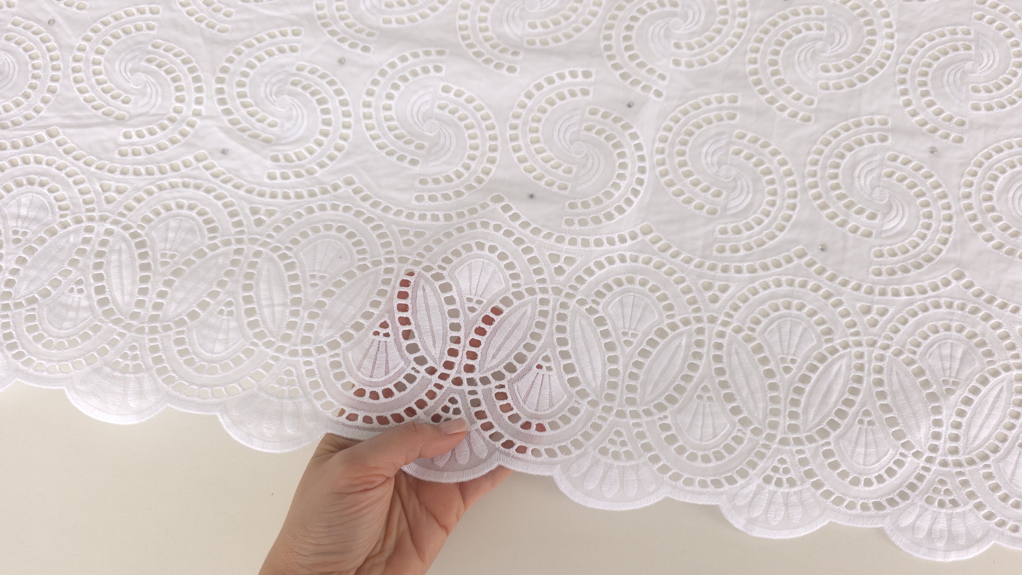 Detaliu bordură scalop cu motive ovale brodate și decupaje pe dantelă albă din bumbac