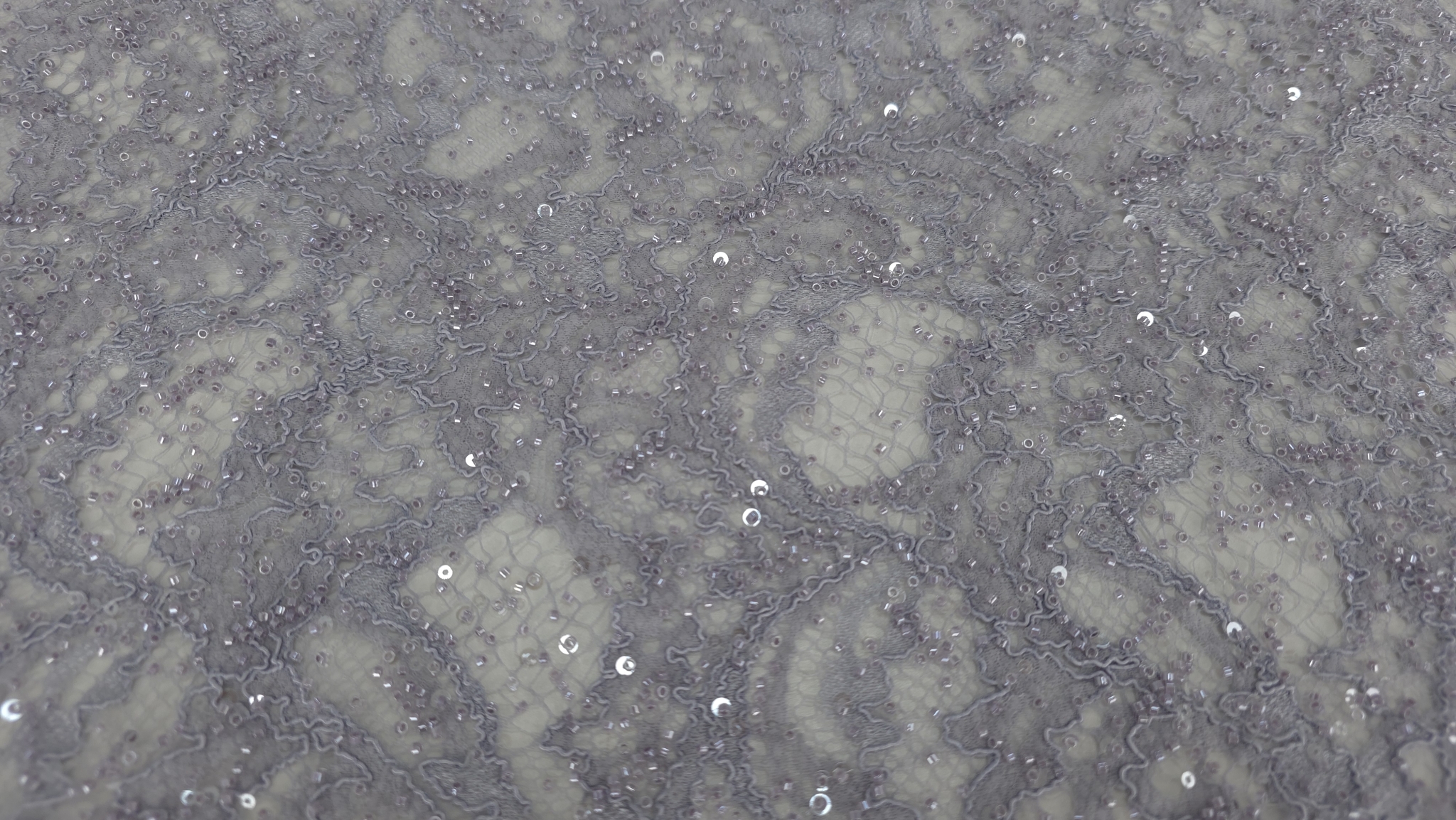 Detaliu macro pe aplicații lucioase distribuite dens pe suprafața broderiei