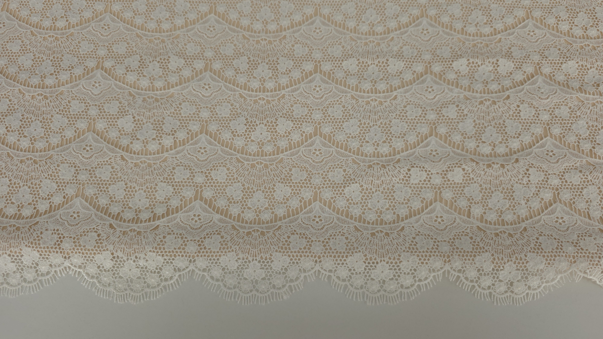 Detaliu pe arcade scalopate cu flori mici si ochiuri regulate ale dantelei macrame ivory