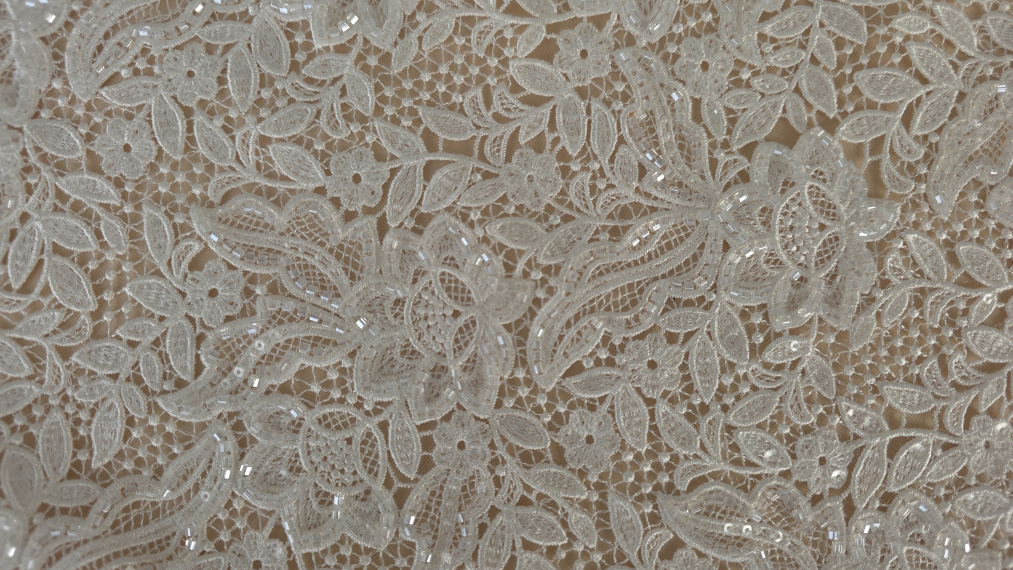 Detaliu pe mărgele translucide fixate între petale și ramuri brodate