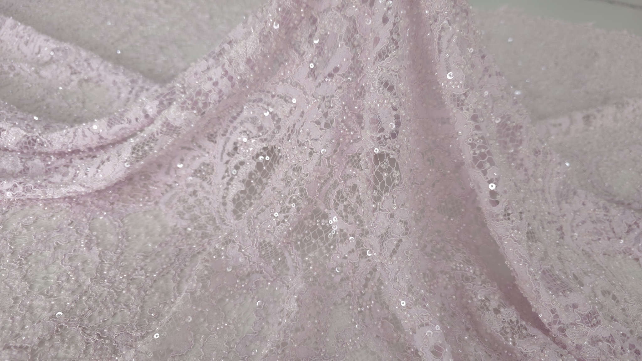 Detaliu plan apropiat pe broderie florală roz pastel cu aplicații transparente