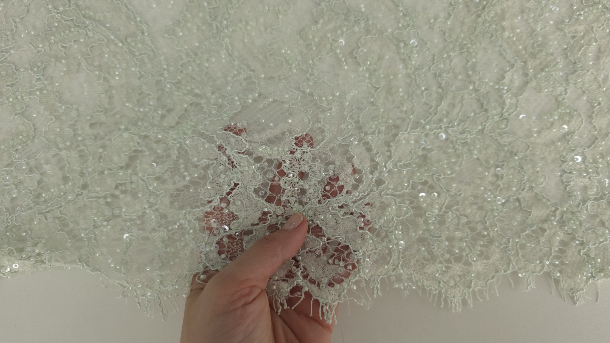 Detaliu plan apropiat pe broderie florală verde pastel cu aplicații transparente