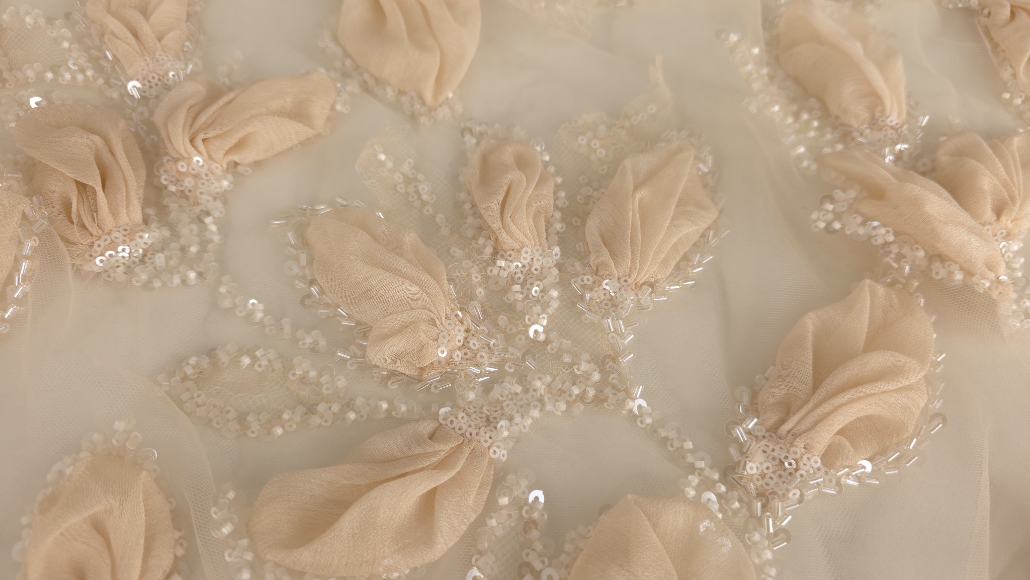 Detaliu ramuri brodate cu paiete și mărgele tubulare între florile 3D peach pe tul transparent
