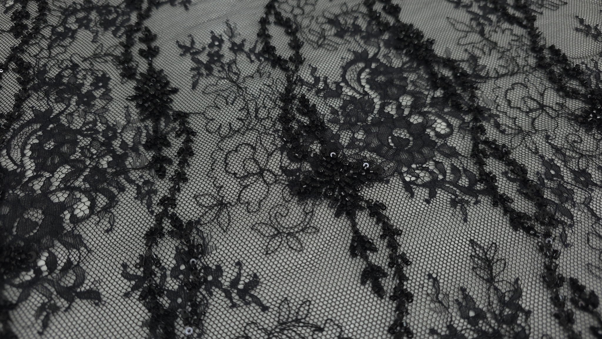 Detaliu textură tul negru transparent cu broderie florală și micropaiete negre