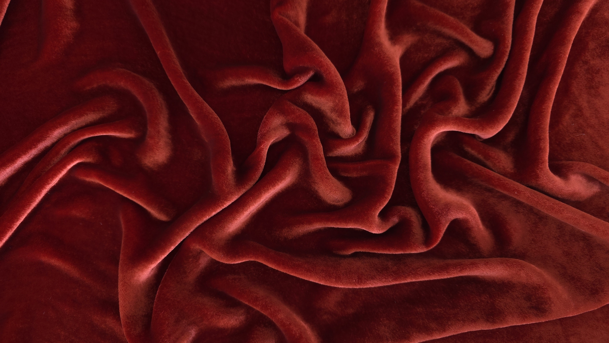 Drapaj amplu de catifea grenadine cu linii curbe și zone de lumină și umbră pe suprafață