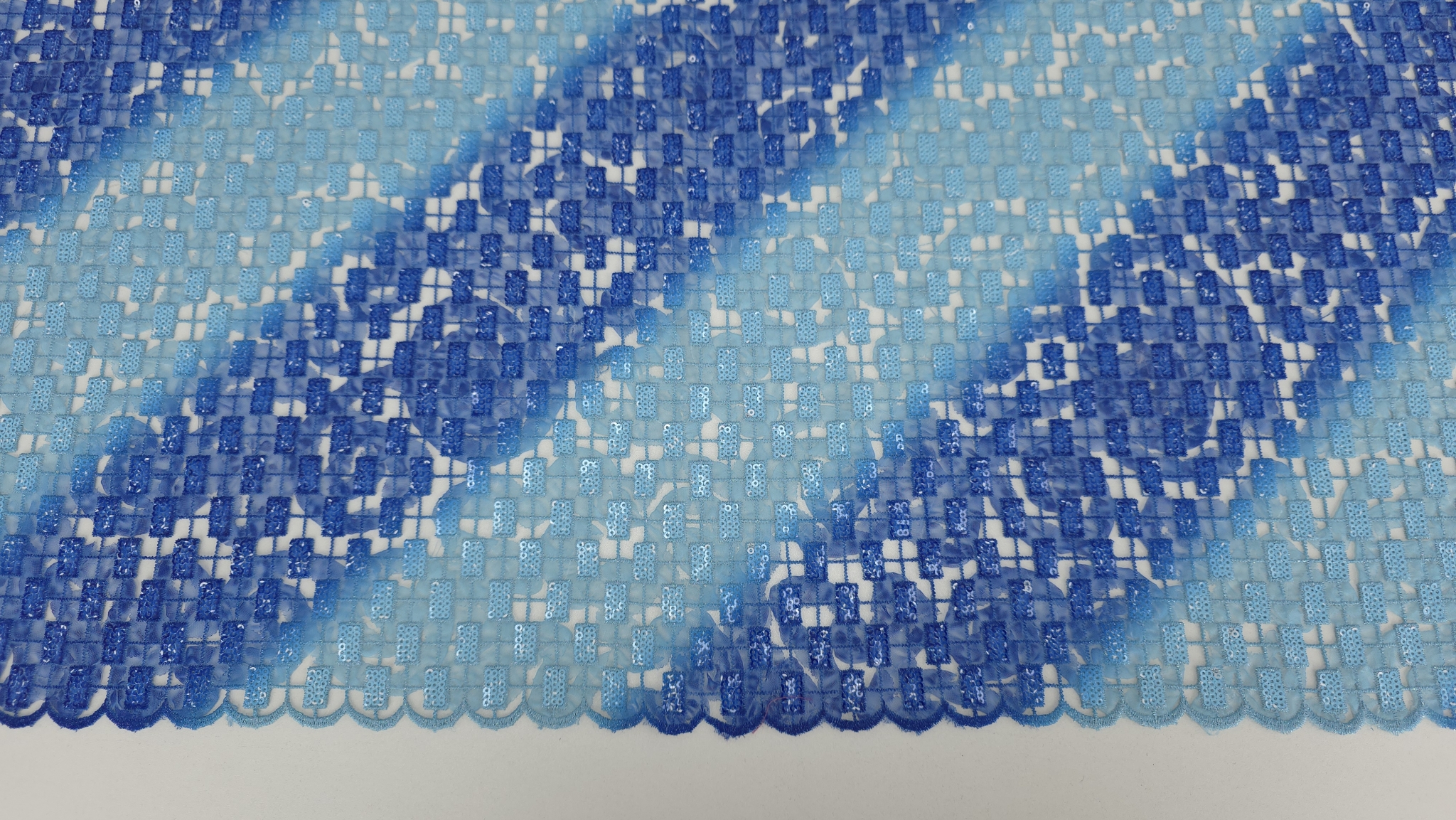 Falduri ale broderiei albastre degrade cu benzi diagonale și paiete pe fond transparent